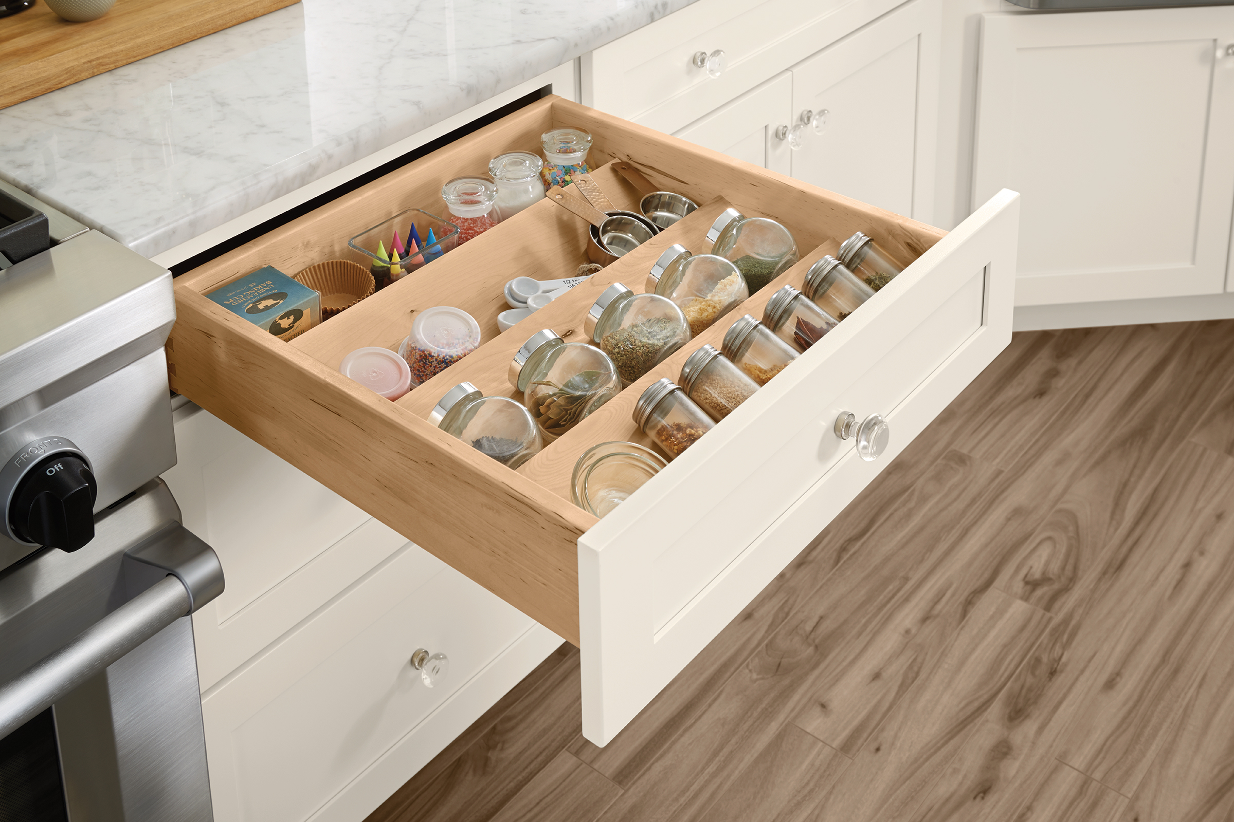 KraftMaid base cabinet with top drawer opened to reveal organized kitchen drawer spice rack insert for storage