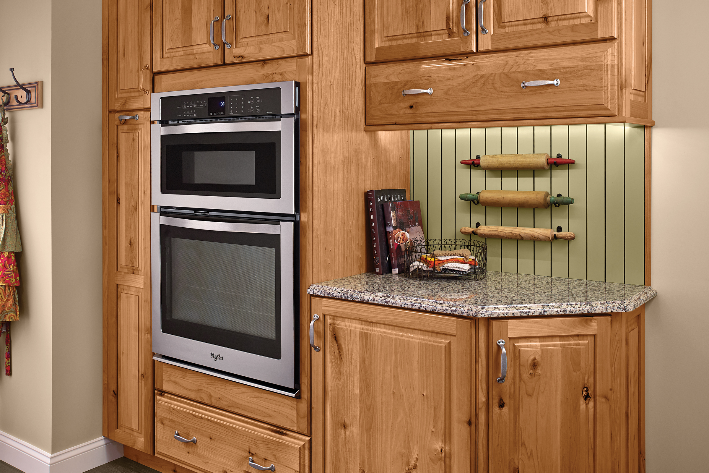 Cooking workstation anchored by a tall KraftMaid wall-oven cabinet in Rustic Alder with a Natural finish
