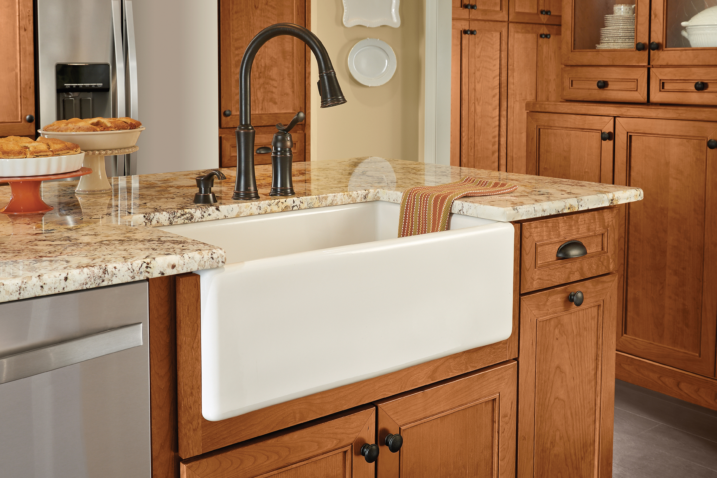 Farmhouse-inspired KraftMaid kitchen design with glass-door display Praline stained hutch and center island with tapered legs